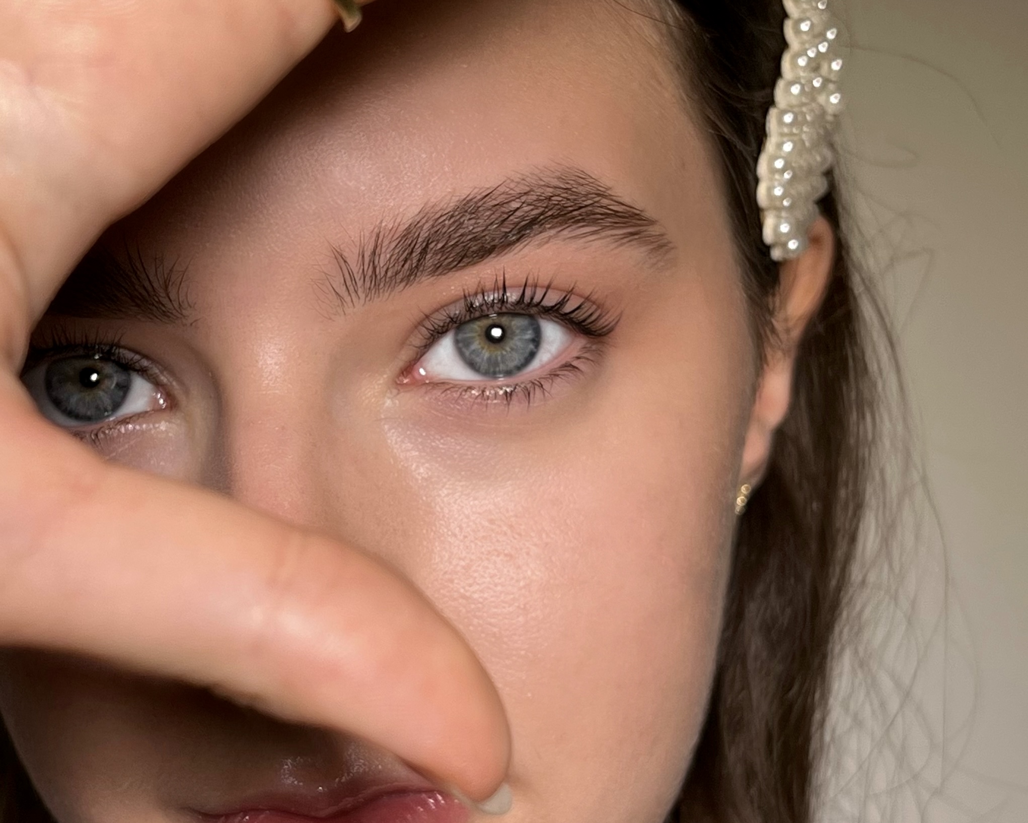 Elegantes Brow Styling mit blauen Augen und Perlen-Haarreif